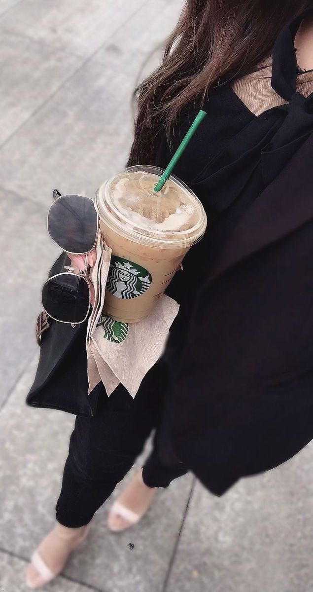 a woman holding a cup of coffee and sunglasses