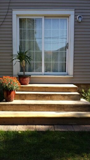 a house with steps leading up to the front door and flower pots on the porch