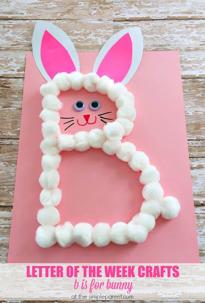 the letter e made out of paper and yarn with bunny ears on it, sitting on top of a pink sheet of paper