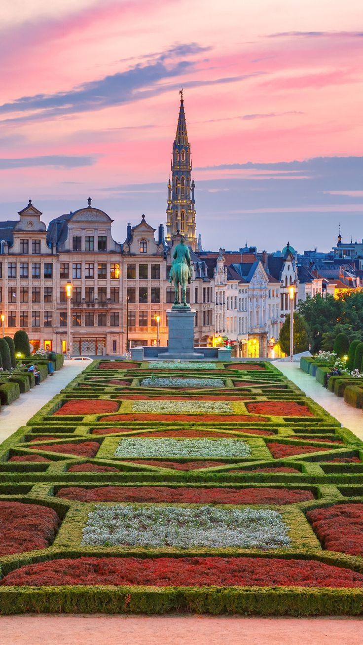 a large garden in front of a tall building with a clock tower on it's side