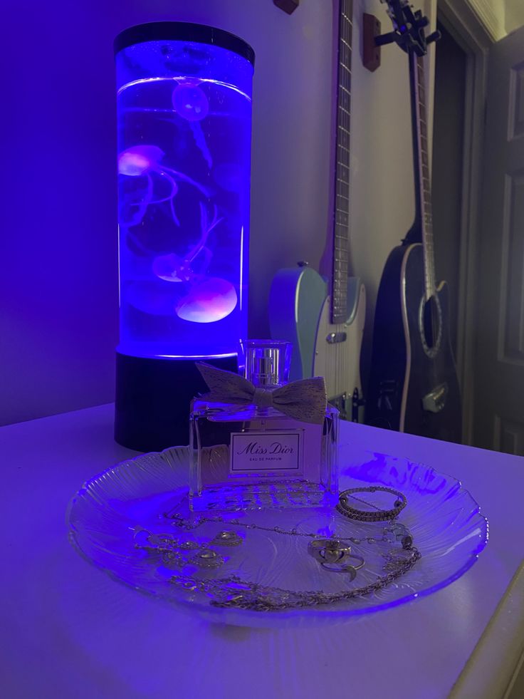 a purple light is shining on a glass plate with some jewelry in front of it