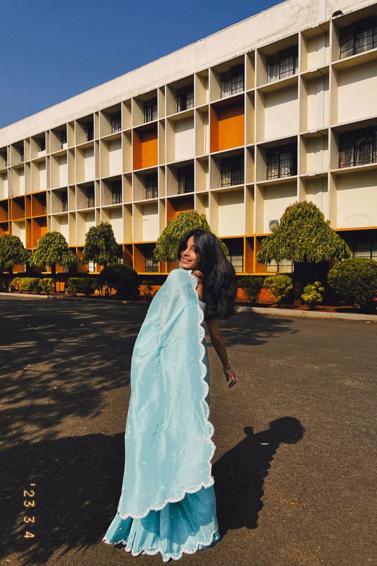 a woman standing in the middle of an empty parking lot wearing a long blue dress