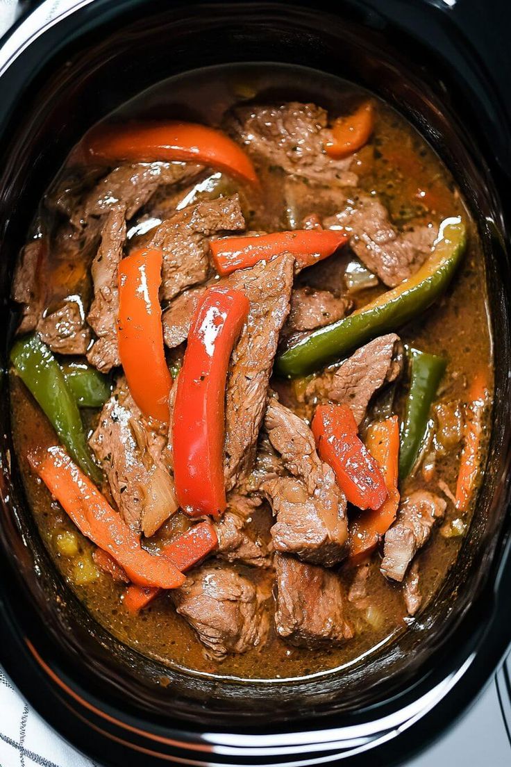 a pot filled with meat and peppers on top of a stove