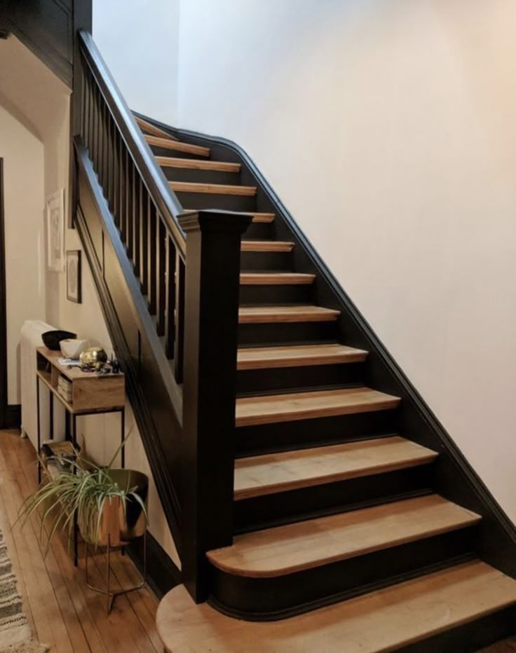 there is a stair case on the side of this staircase next to a table with a potted plant