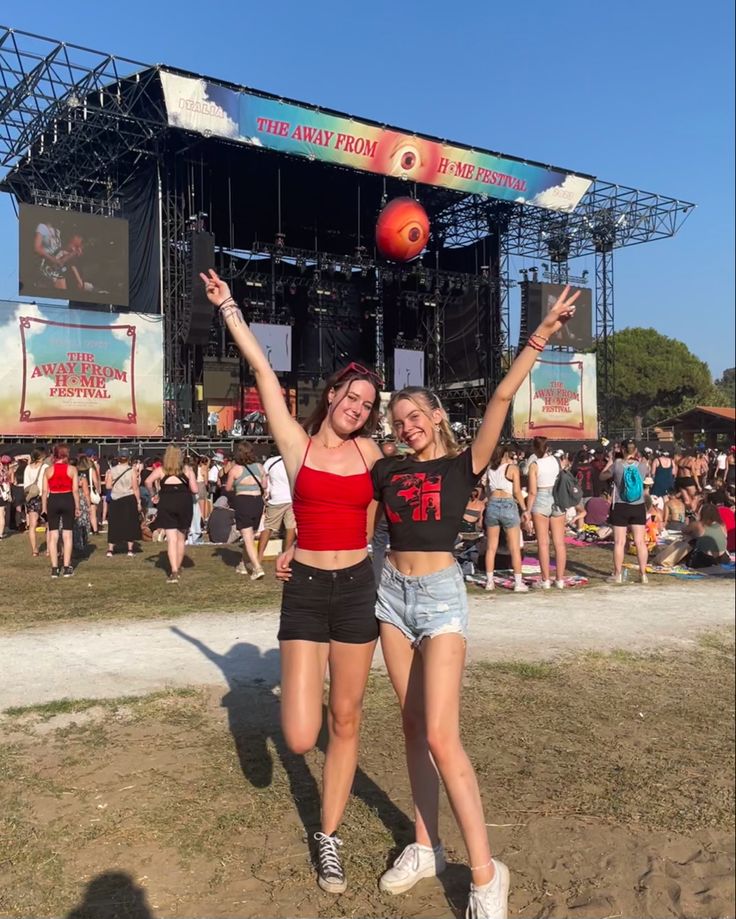 two women standing in front of a stage at a music festival