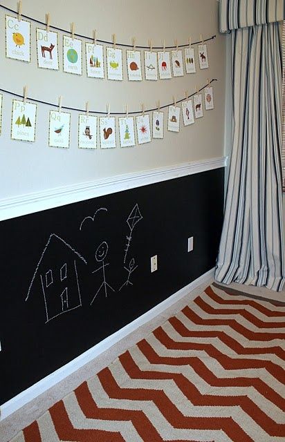 a child's room decorated in black, white and orange with pictures on the wall