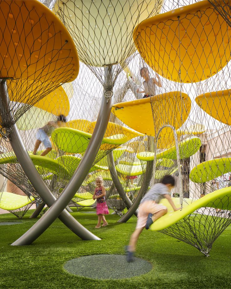 people are playing in the grass with yellow chairs and umbrellas on display at an art museum