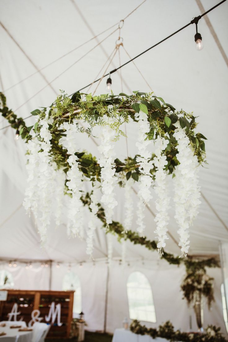 an elegant chandelier with white flowers and greenery hanging from it's ceiling