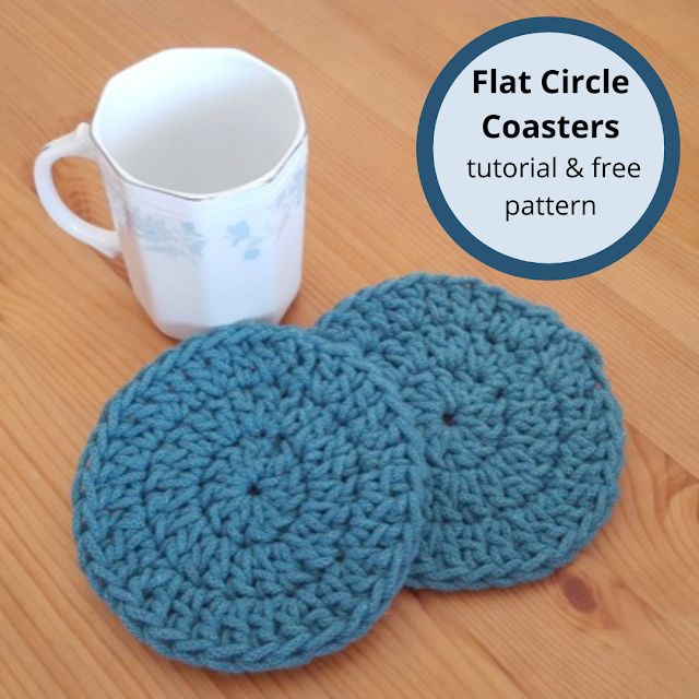 two crocheted coasters sitting on top of a wooden table next to a cup