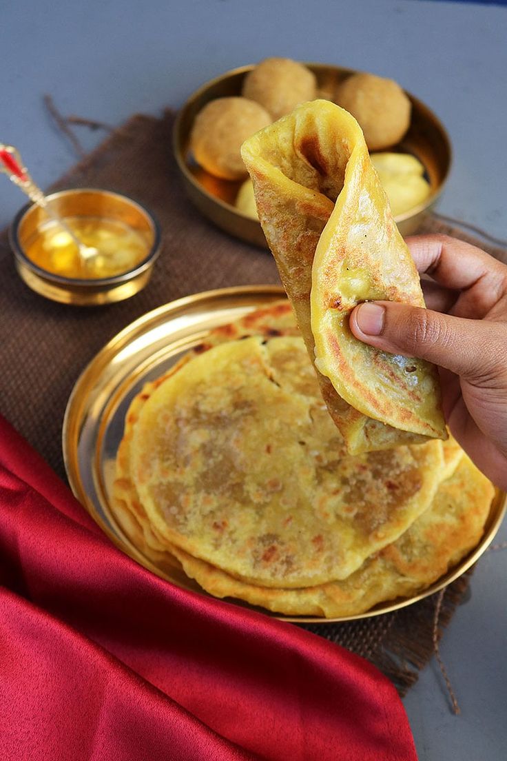 a person is holding some food in their hand and there are other foods on the table