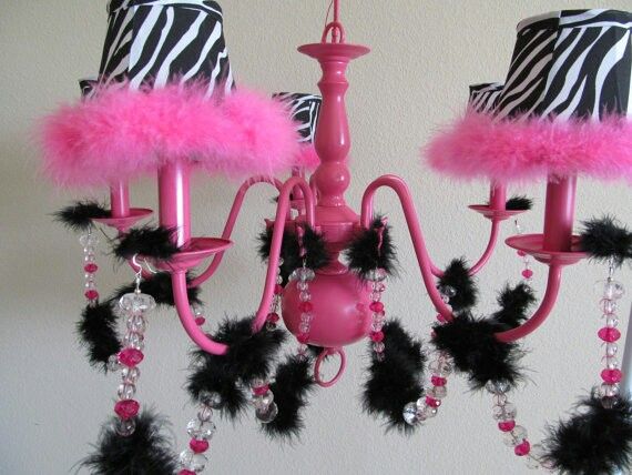 a pink chandelier with zebra print lampshade and black feathers on it