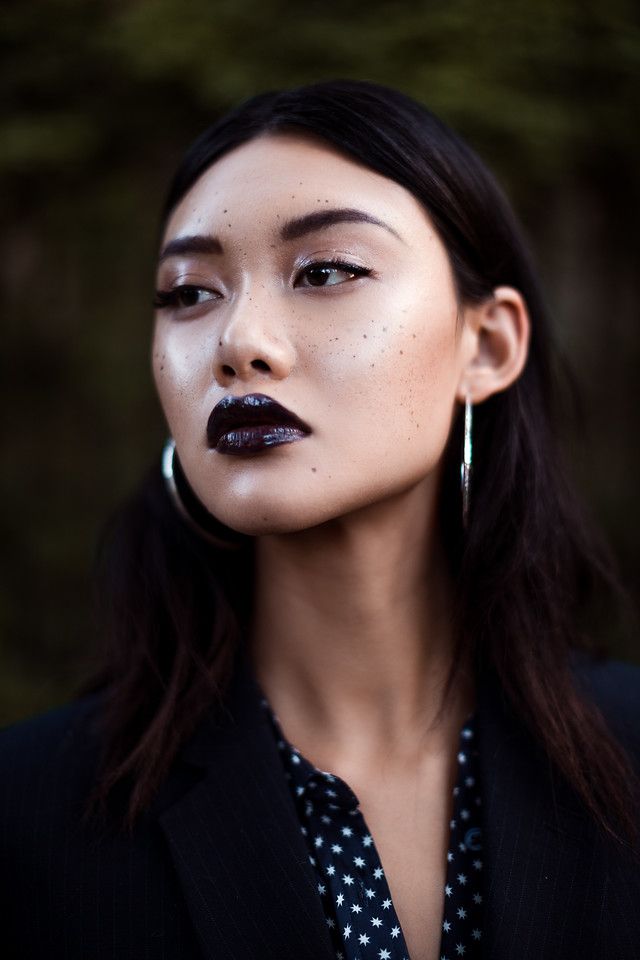 a woman with black lipstick on her face and long dark hair is posing for the camera