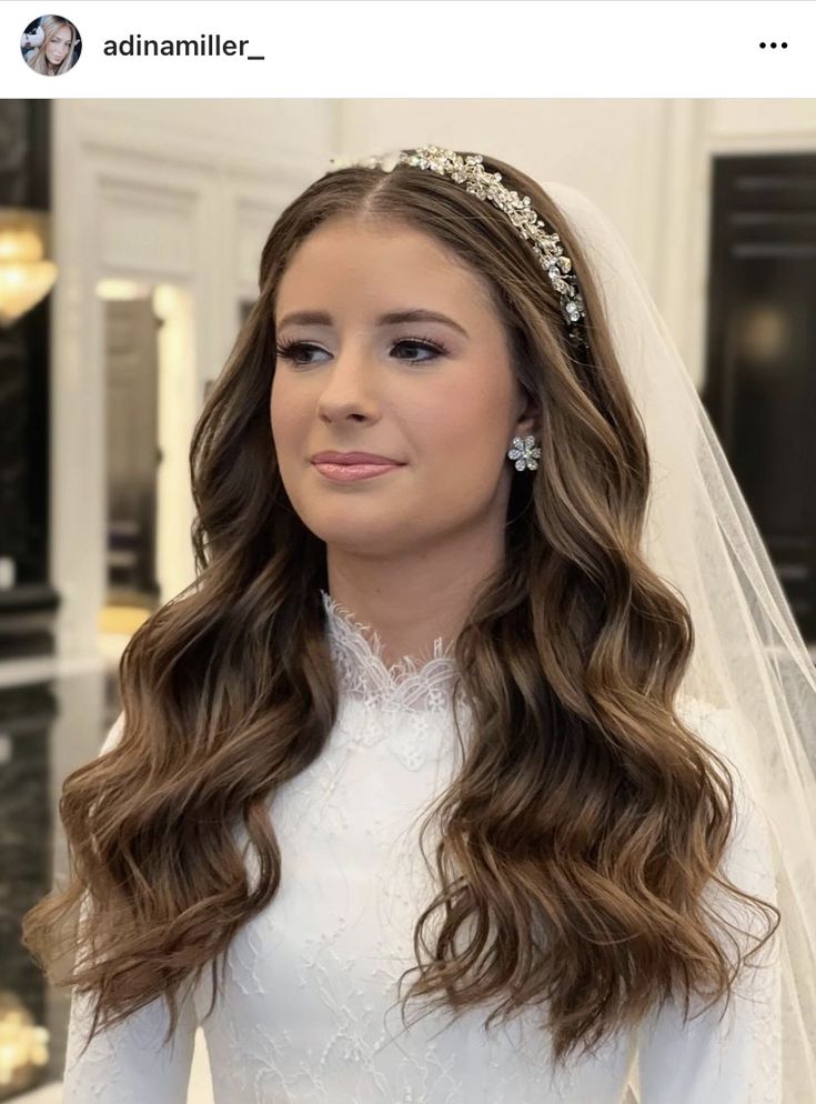 a woman with long hair wearing a wedding dress and tiara, looking at the camera