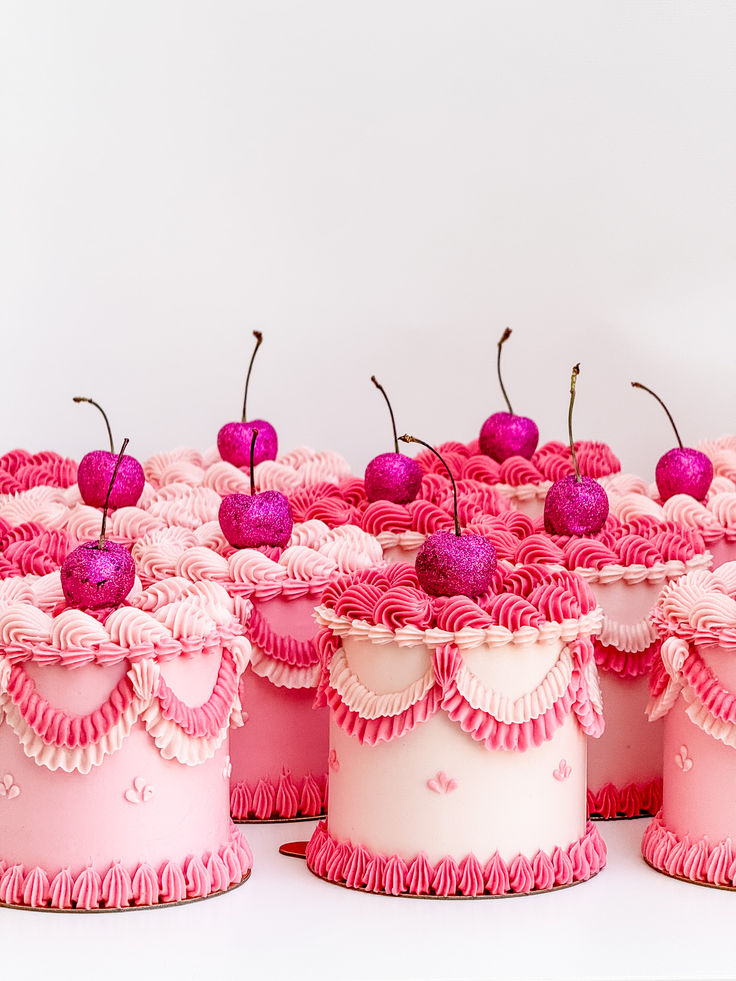 pink cupcakes decorated with cherries and ruffles are arranged on top of each other