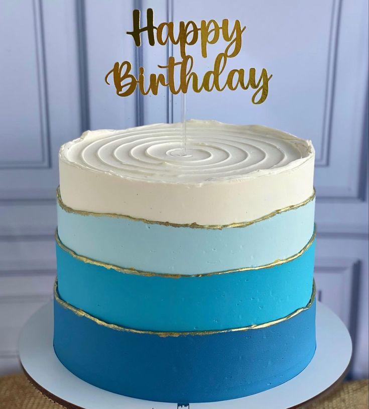 a blue and white cake with a happy birthday topper on it's side