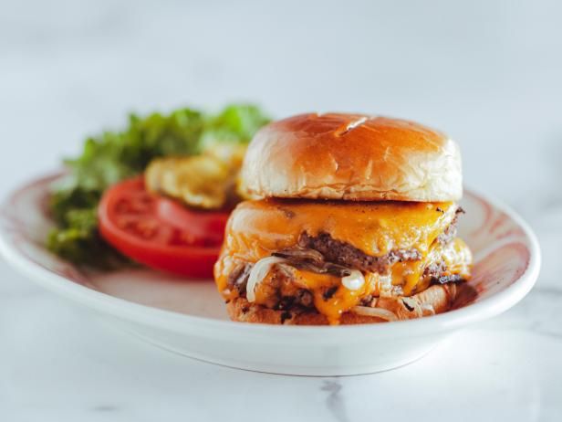 a white plate topped with a cheeseburger and tomatoes