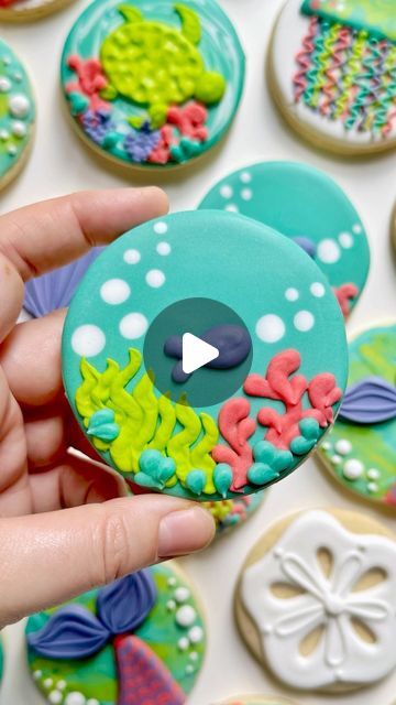 a person is holding some decorated cookies in their hand and pointing to the video screen