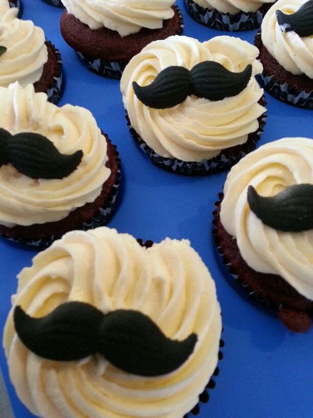 cupcakes with white frosting and black moustaches on blue tray