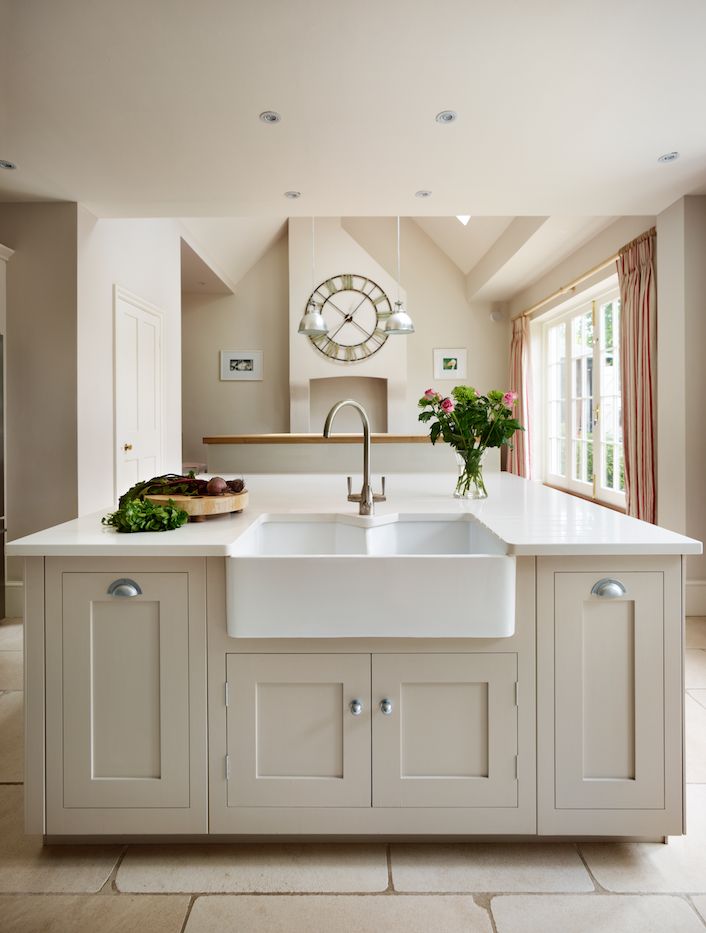 a kitchen with a large white sink and counter top next to a clock on the wall