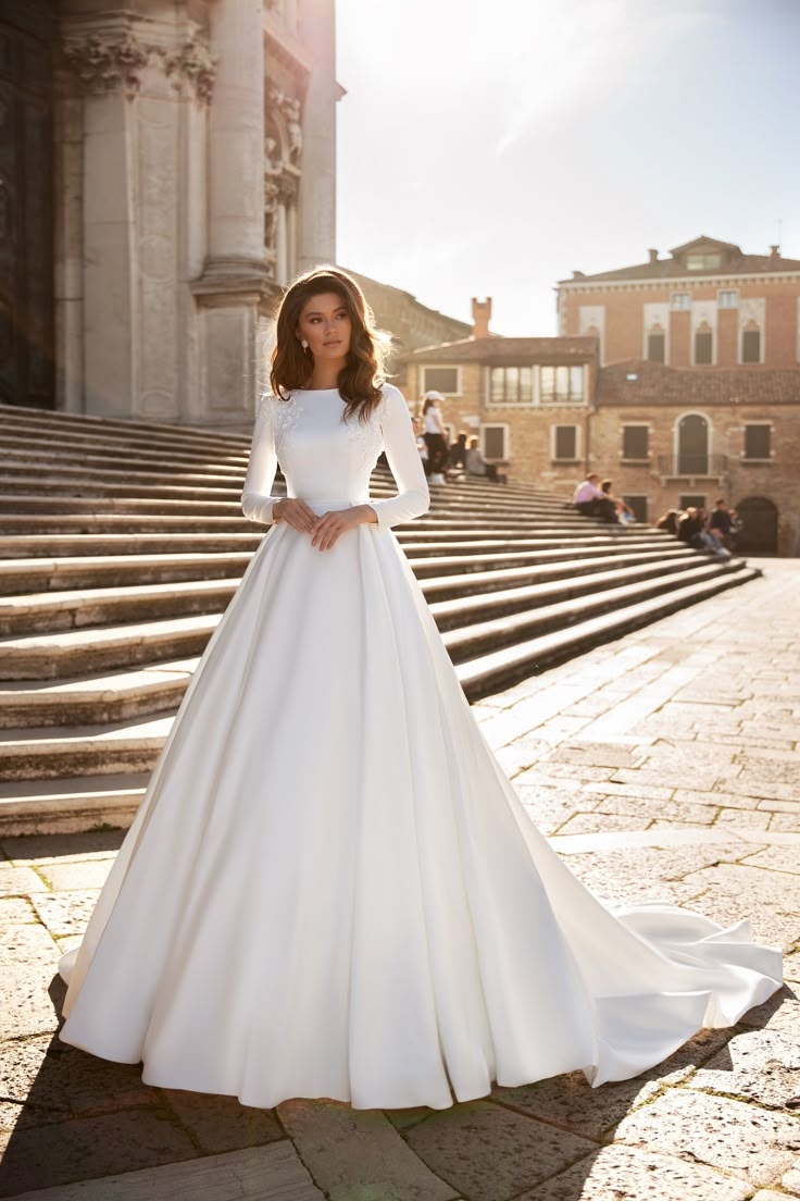 a woman in a white wedding dress standing on steps