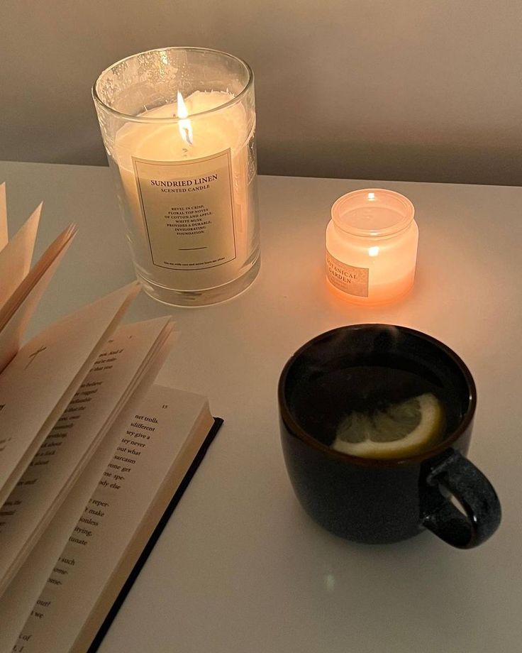 a candle and some books are sitting on a table next to a cup of coffee