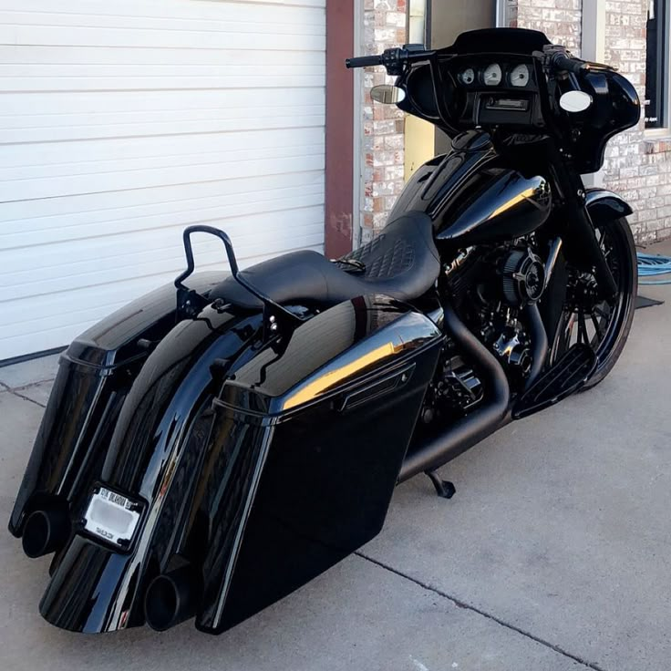 a black motorcycle parked in front of a garage