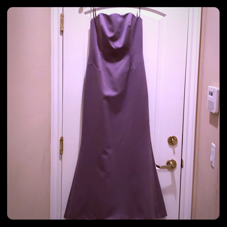 a purple dress hanging on a door with a hanger in front of the door