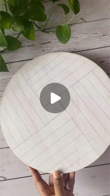 a person holding up a white plate with a video on it and green plants in the background