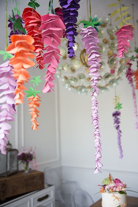 a bunch of paper flowers hanging from the ceiling in front of a white wall with an instagram message below