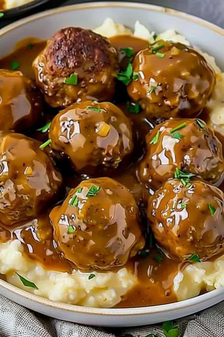 meatballs and mashed potatoes with gravy in a white bowl on a table