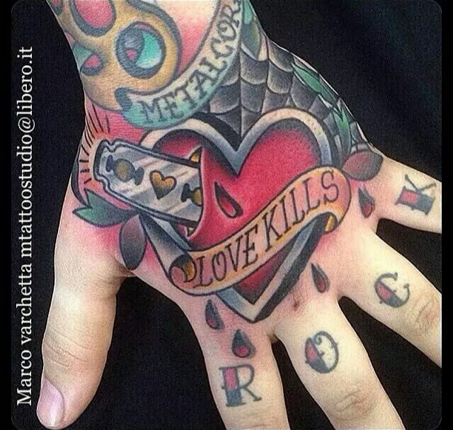 a person with tattoos on their hand holding up a heart and arrow tattoo design that says love kills