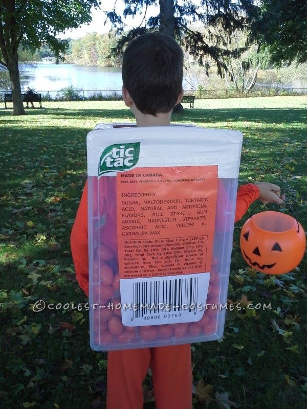 a young boy in an orange shirt holding a bag of candy