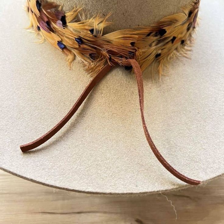 The Stellar Western Feather Hat Band, measuring 3 cm in width and approximately 58 cm in length (excluding the leather ties), offers a refined touch to any hat. Designed to fit most, it features adjustable leather ties for a secure and comfortable fit. The center crown, measuring 2.5" W x 2.25" H, adds a distinctive element, while the feather detailing brings a touch of rustic charm, making this hat band a stellar addition to any western-inspired wardrobe. Cowgirl Dress Up, Feather Hat Band, Cowboy Hat Band, Feather Hats, Cowgirl Dress, Cowboy Hat Bands, Black Iridescent, Clothes Steamer, Hat Bands