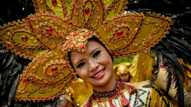 a woman wearing a costume with feathers on her head and smiling at the camera while standing in front of other people