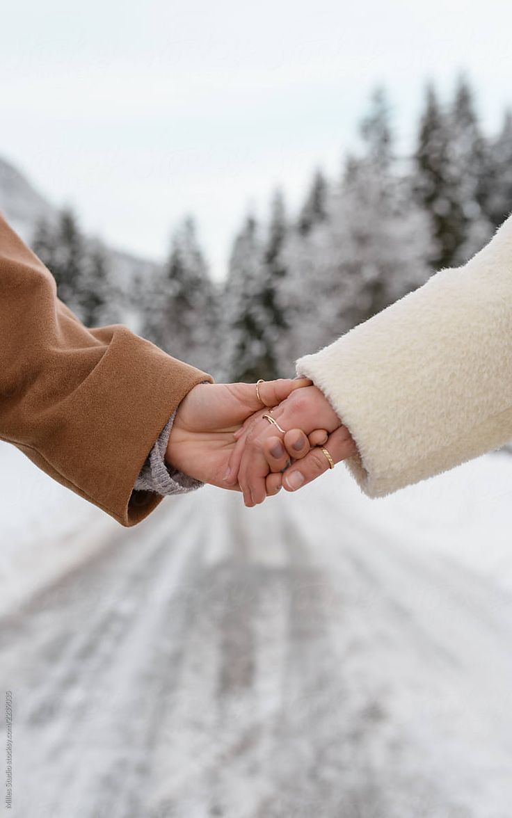 two people holding hands on a snowy road