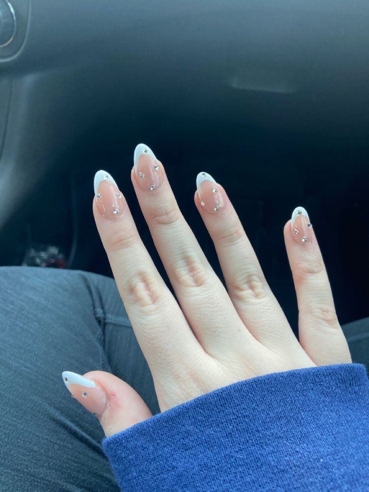 a woman's hand with white and silver nail polish sitting in the passenger seat