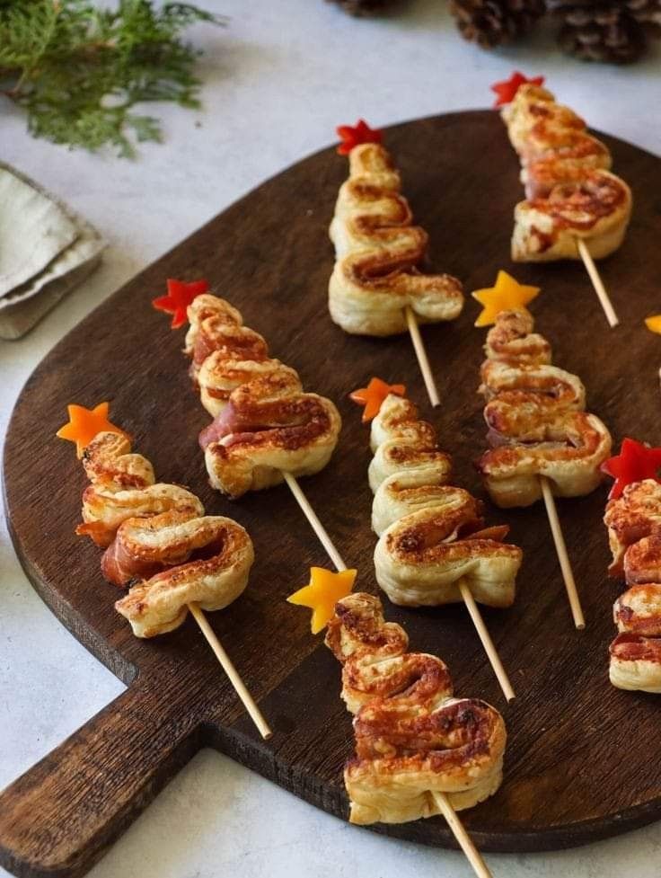 some food is sitting on a wooden platter with toothpicks in the shape of christmas trees