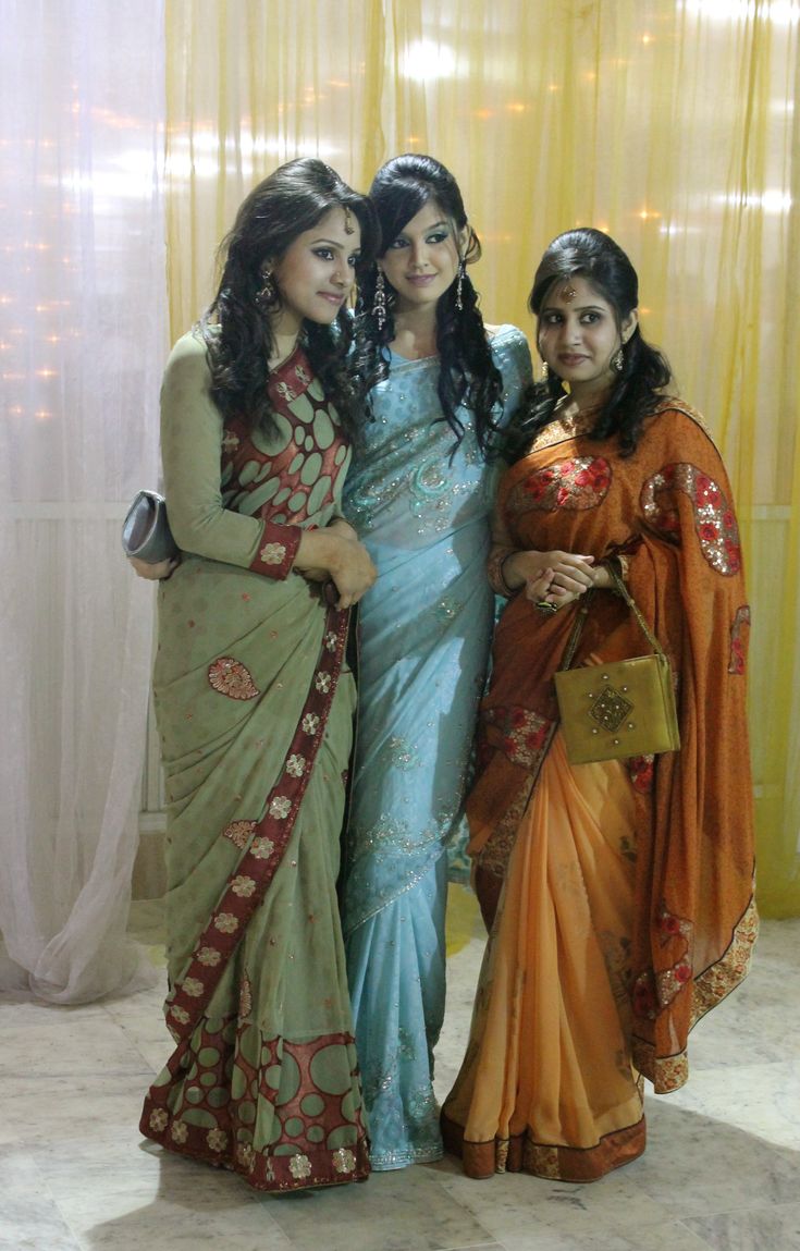 three women standing next to each other in front of a window with yellow drapes