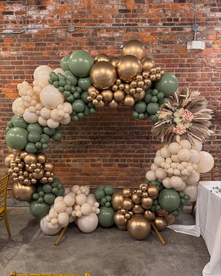 a large wreath made out of balloons and greenery in front of a brick wall