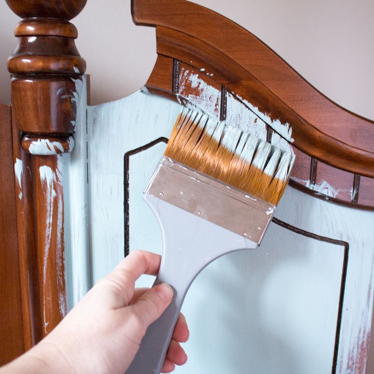 a person holding a paint brush in front of a mirror with white paint on it