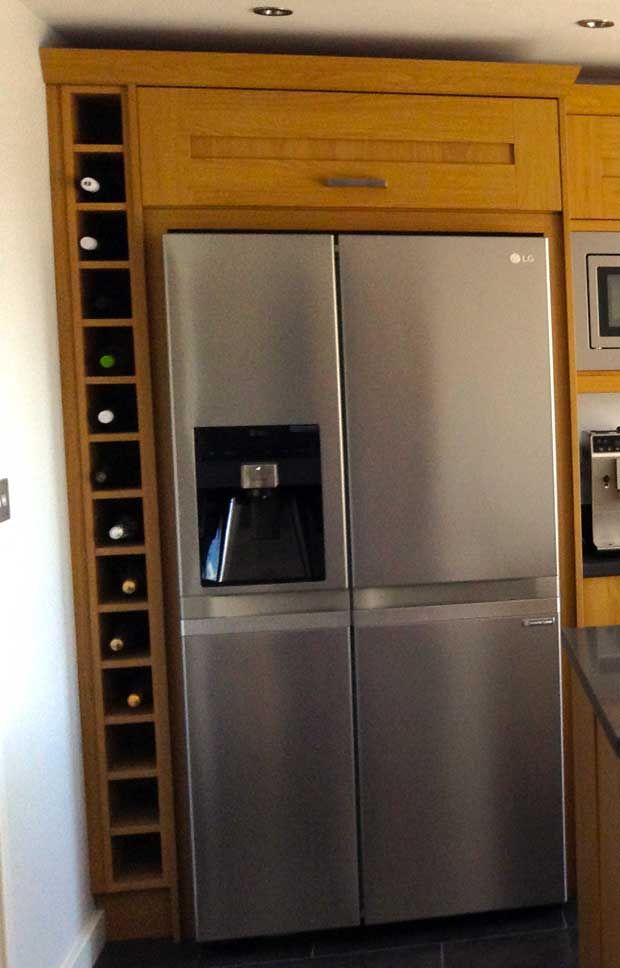 a stainless steel refrigerator freezer sitting inside of a kitchen next to a wine rack