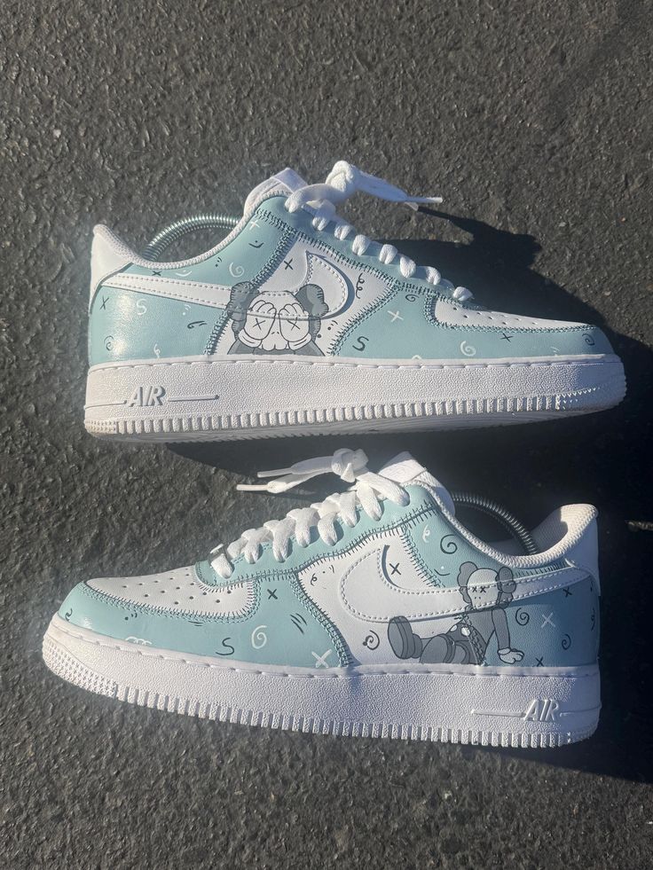 These custom Kaws-inspired Air Force 1 sneakers feature a stunning Prelude Gray and white color scheme with intricate hand-painted Kaws graphics. The iconic Companion character is showcased in detail, blending effortlessly with the swirling abstract designs and signature 'X' motifs across the shoes. Made with precision and creativity, these one-of-a-kind kicks offer a unique blend of street art and high fashion, perfect for sneakerheads and art lovers alike. Custom Air Force Ones Design, White Sneakers With Graffiti Print For Sports, Sporty White Custom Sneakers With Graffiti Print, White Custom Sneakers With Graffiti Print, White Sporty Sneakers With Graffiti Print, Sporty White Sneakers With Graffiti Print, White Low-top Graffiti Sneakers, Artistic Low-top Sneakers With Custom Artwork, White Low-top Sneakers With Graffiti Print