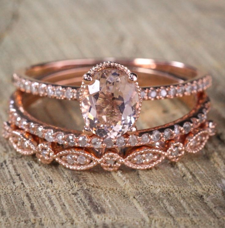 two wedding bands with an oval cut diamond in the center and side stones on each band