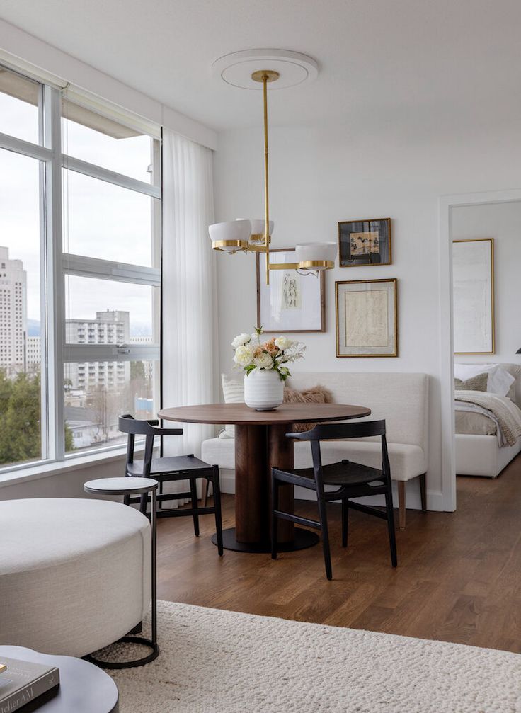 a dining room table and chairs in front of a large window with cityscape behind it