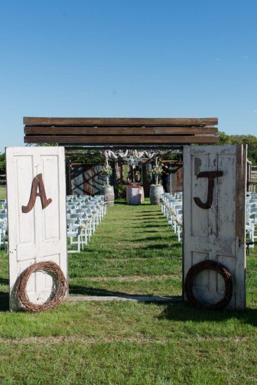 an outdoor wedding venue with chairs and wooden doors that have the initials j and t painted on them