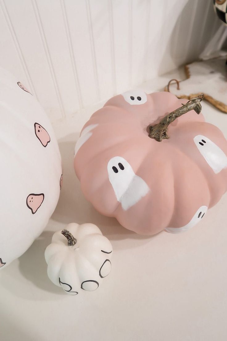 two white pumpkins sitting on top of a table next to each other with faces painted on them