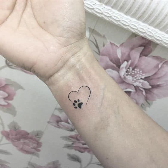 a small tattoo on the wrist of a woman's arm with a heart and paw prints