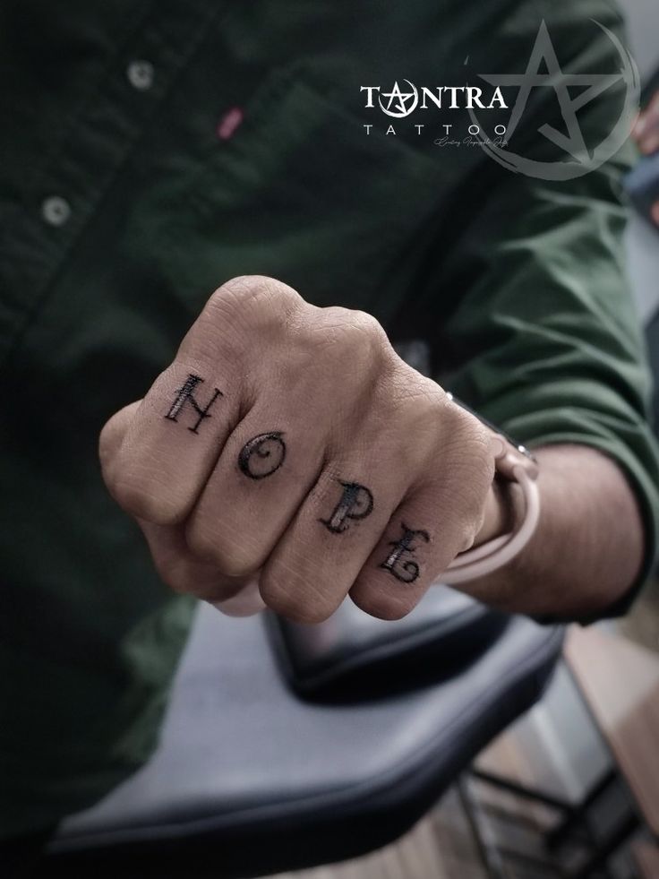 two fingers with the words hope and hope tattooed on each finger, in front of a chair