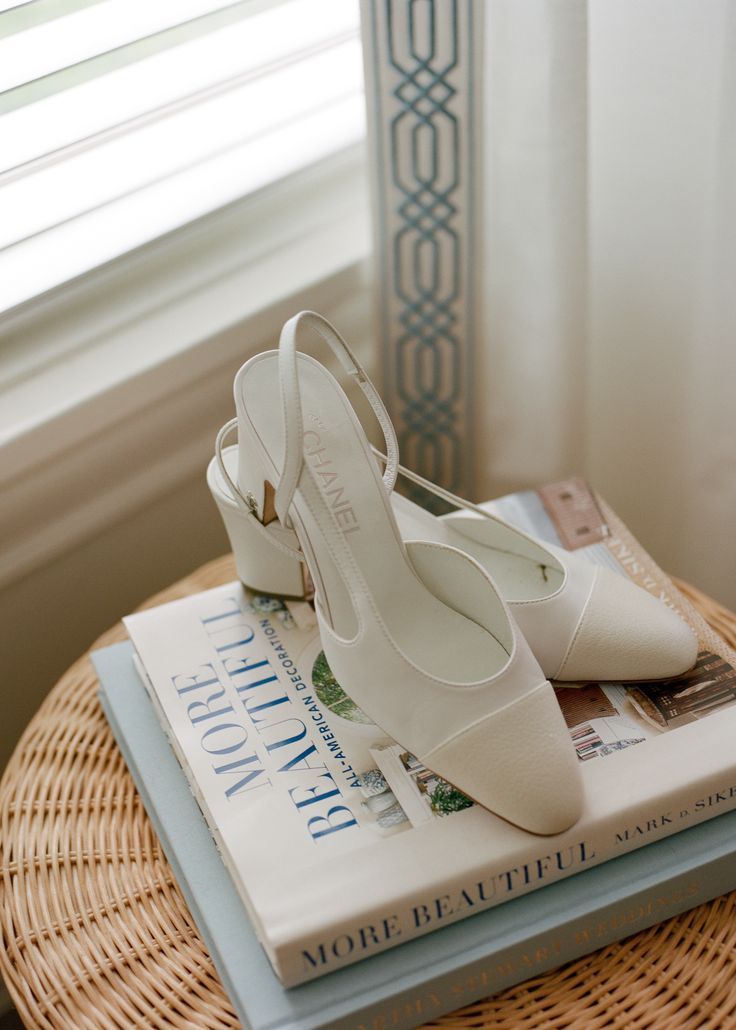 a pair of white shoes sitting on top of a stack of books