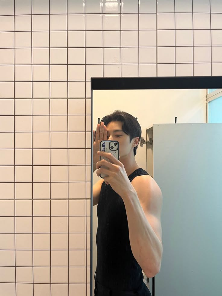 a man taking a selfie in front of a bathroom mirror with his cell phone